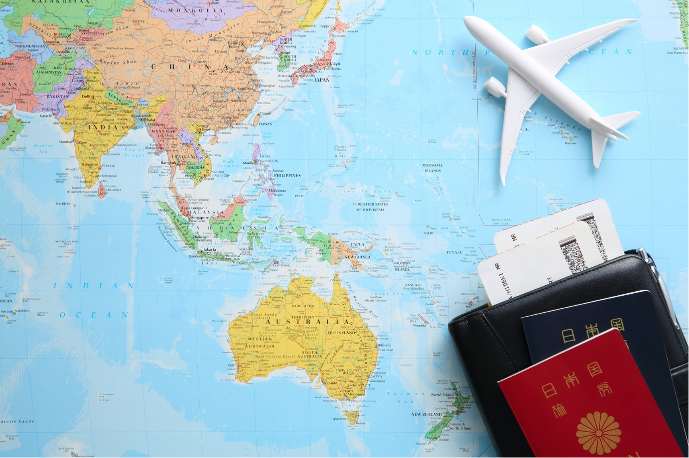 A world map with a model airplane, passport, and travel documents ready for a trip
