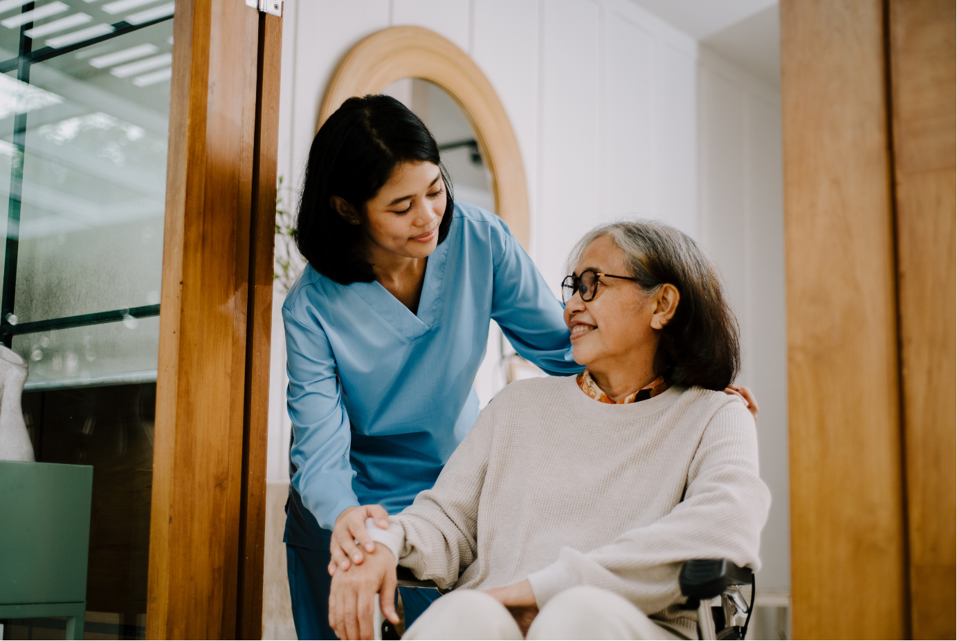 A caregiver comforting a senior woman in a wheelchair